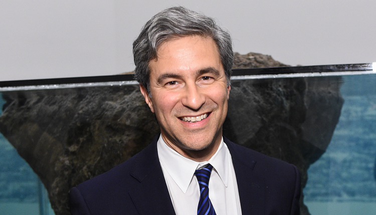 Portrait of the blog owner with face partially distorted through two clear glasses of water on a white table